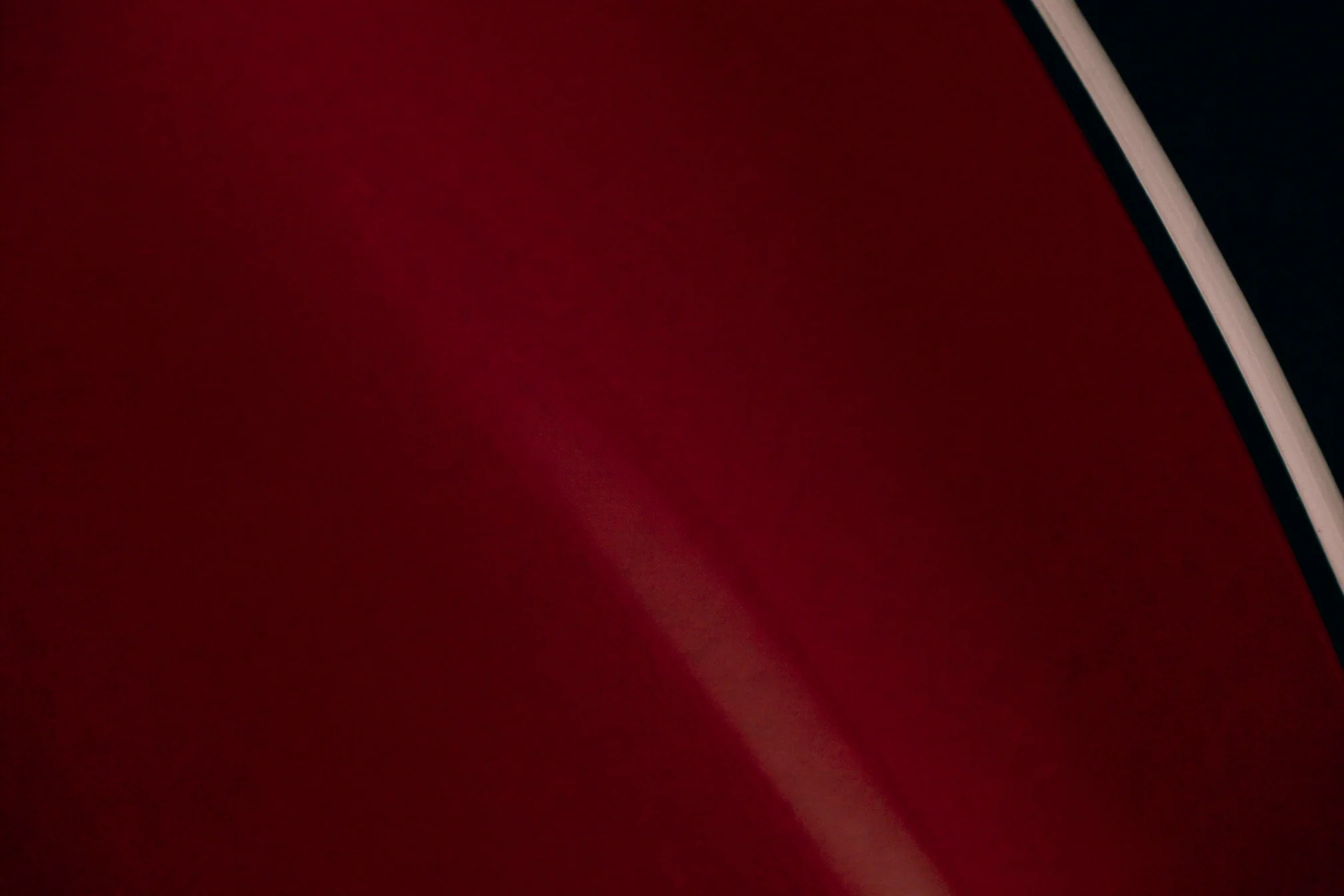 Cinematic close-up of crimson automotive paint and chrome trim
