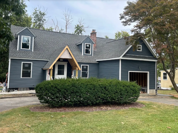 Supplied photograph of a blue-gray house with a shingled roof and timber entry