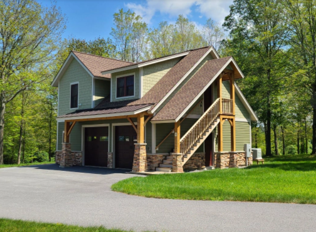 Green two-story building with intersecting rooflines, timber posts and stone-clad supports